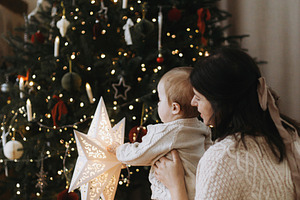 Stylish mother and baby son in knitted sweaters sitting together, a Holiday Photo by Sonjachni