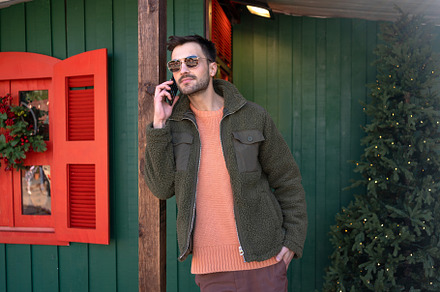 Handsome man talking on smartphone near Christmas tree, a Person Photo by andreonegin market