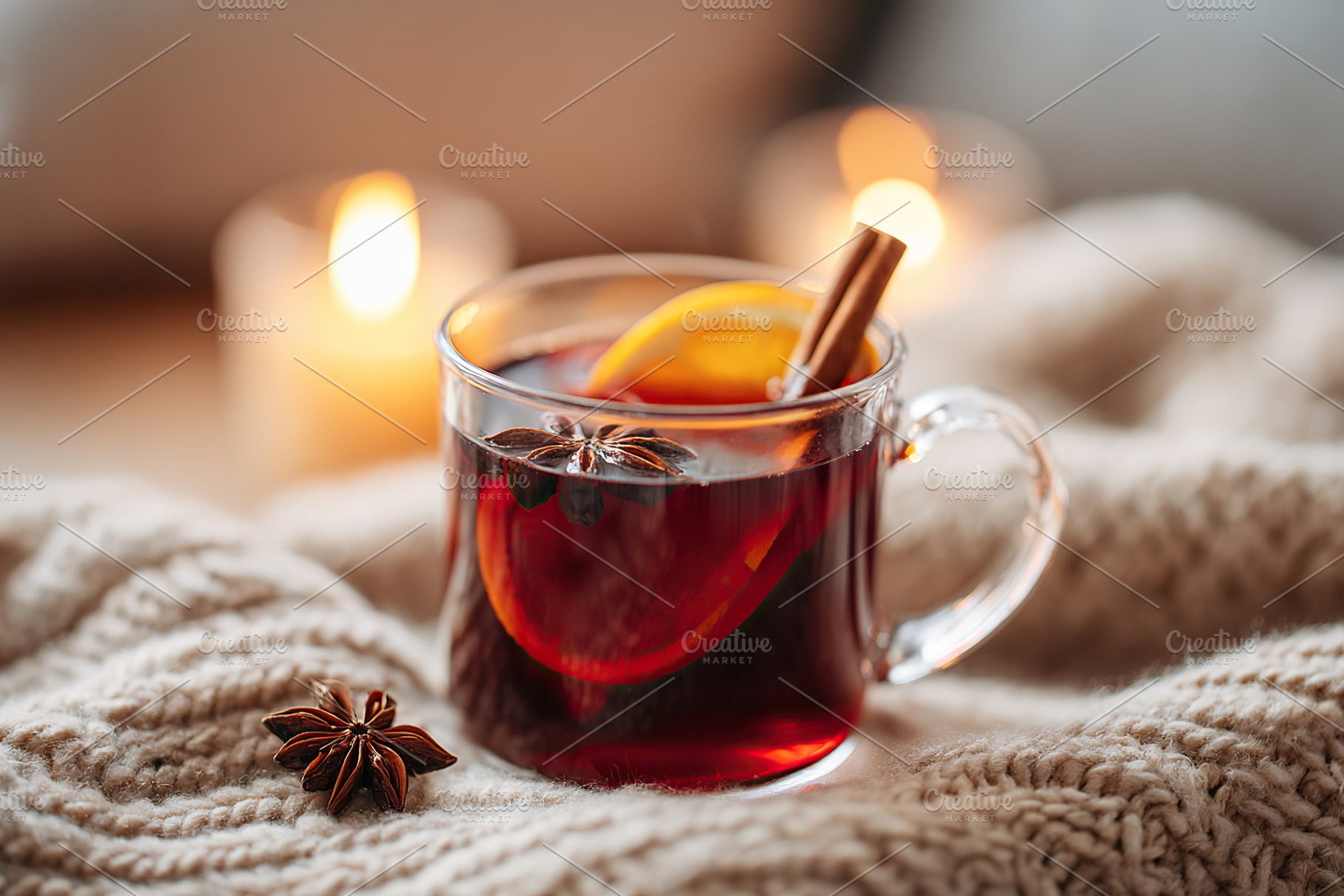 Warm drink with spices and orange slice on cozy blanket beside glowing candles, a Photo by AlyaAnd