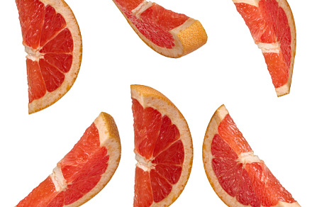 Several sliced red grapefruit wedges from different angles