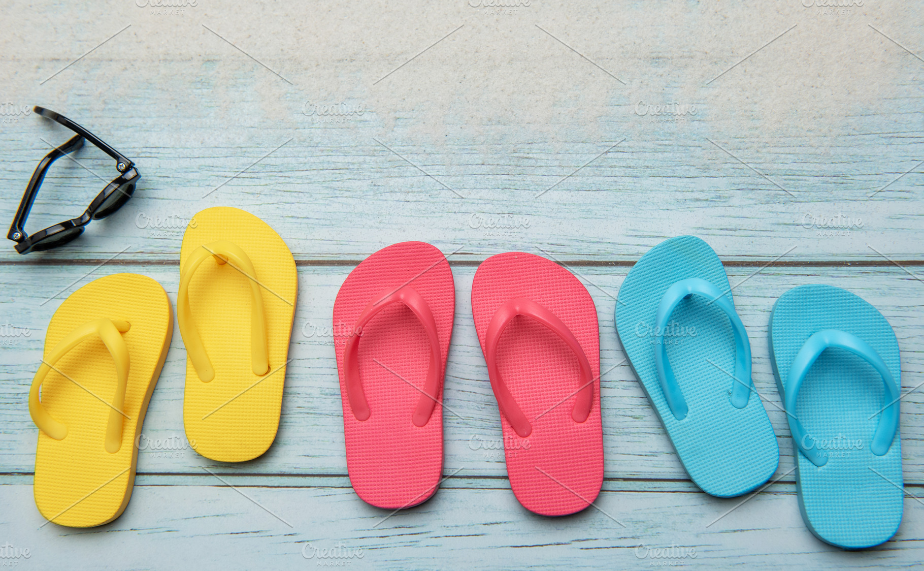 Colorful flip flops and sunglasses resting on beach boardwalk, e, a Holiday Photo by Olena Rudo