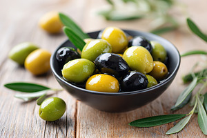 Marinated black and green olives served in a bowl on a rustic wooden table, a Food & Drink Photo by AlyaAnd