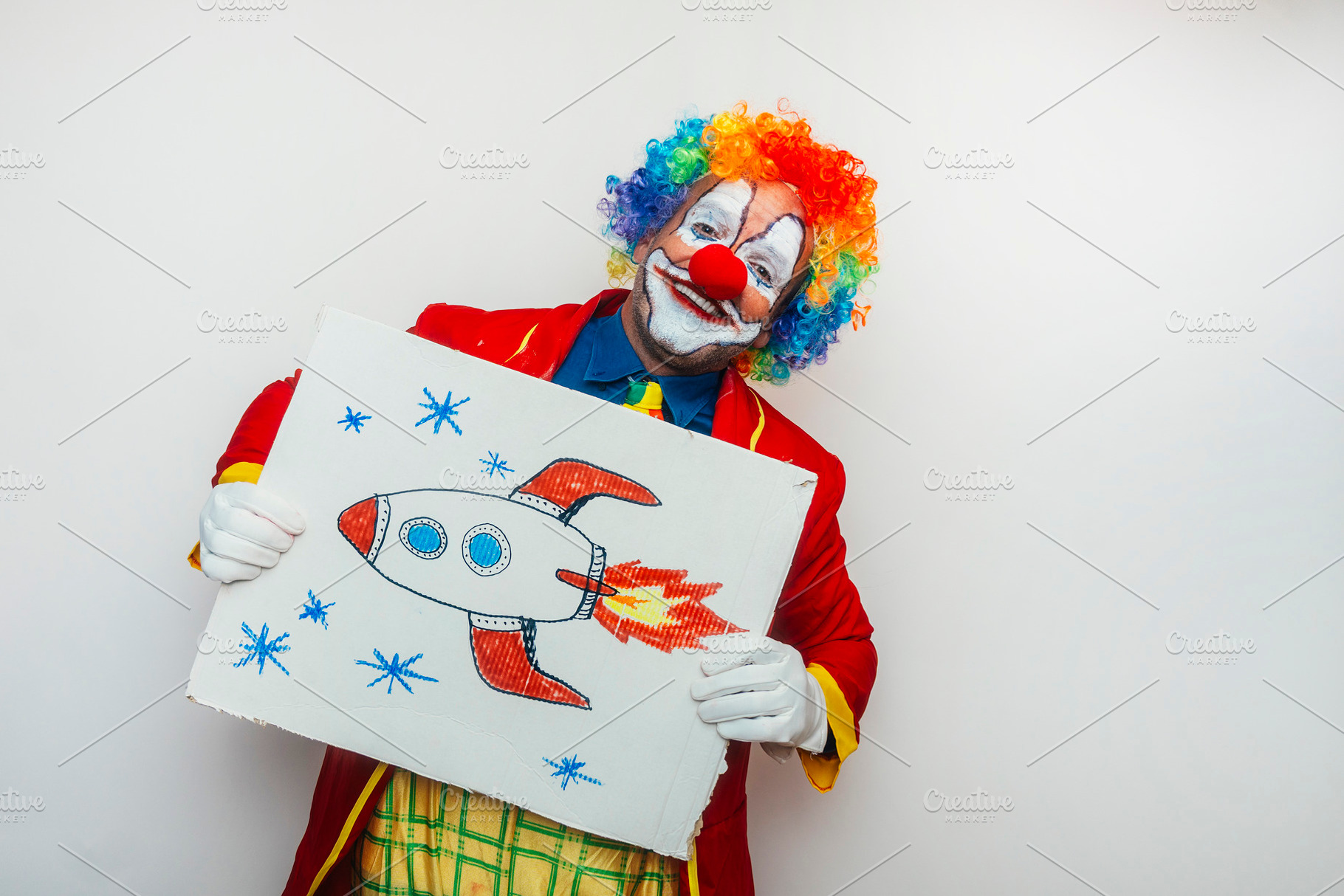 Clown holding cardboard with drawing, a Person Photo by karrastock