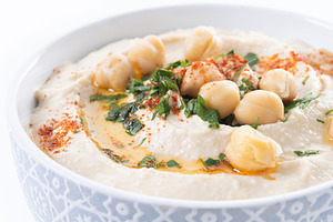 Chickpea hummus with olive oil, parsley and paprika in bowl on wooden table, a Food & Drink Photo by etorres69