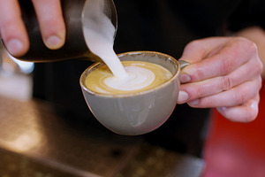 Latte art pouring foamed milk barista hand cup, a Person Photo by Photo Drive Studio