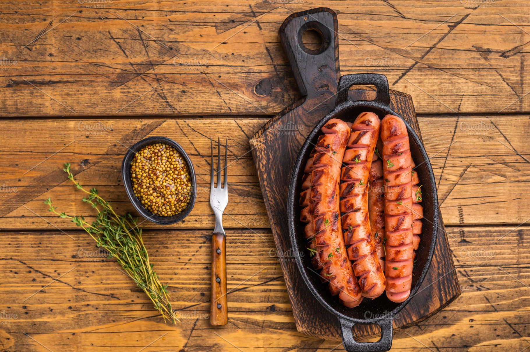 Juicy, smoky fried sausages on a wooden board with herbs and for, a Food & Drink Photo by composter-box@mail.ru