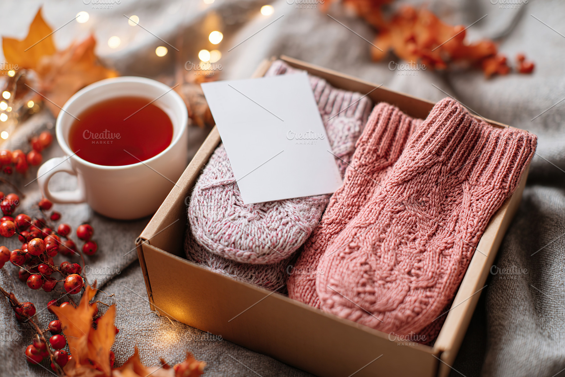 Cozy autumn-themed care package with warm socks and tea in a rustic setting, a Photo by AlyaAnd