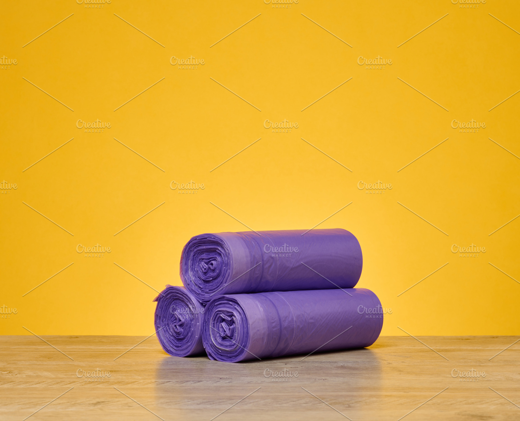 Three rolls of purple garbage bags stacked in a pyramid on a woo, a Background Photo by ndanko