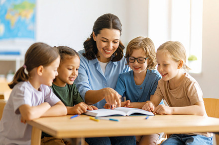 Teacher with a small group of children in a classroom pointing a, a School & Education Photo by DanFLCreativo