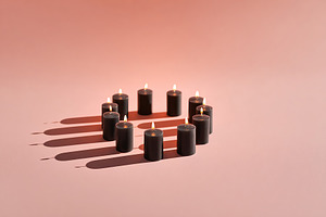 Candles arranged in a circle, casting soft shadows on a warm background, a Photo by AlyaAnd