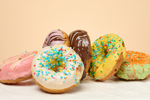 Stack of donuts with different toppings and glazes, beige backgr, a Food & Drink Photo by ndanko