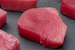 Raw tuna pieces on a black board, snack, a Food & Drink Photo by ndanko
