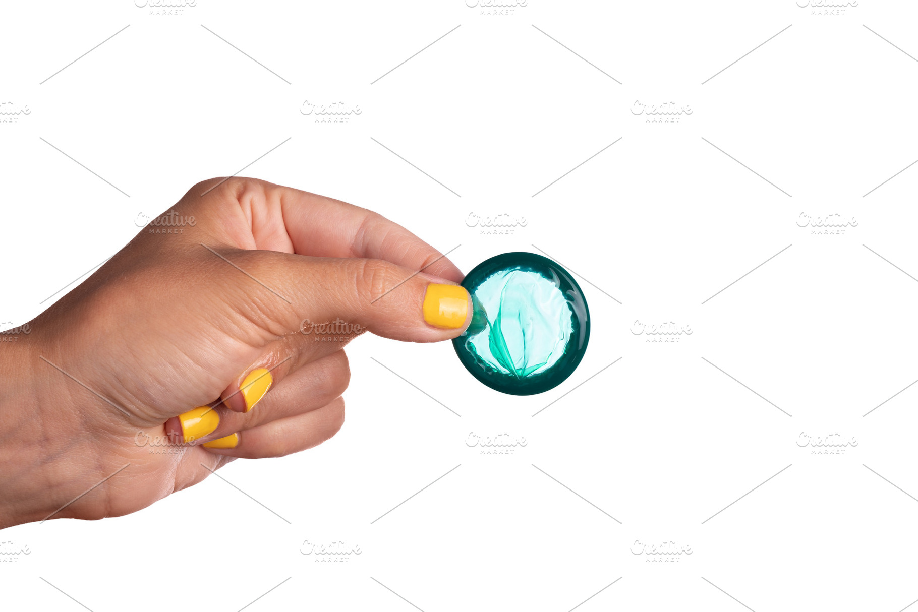 Woman’s hand with yellow nails holding an unrolled teal condom, a Health & Medical Photo by Ales Munt