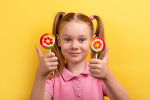 Happy young girl with pigtails holding two colorful lollipops an, a Person Photo by Ales Munt