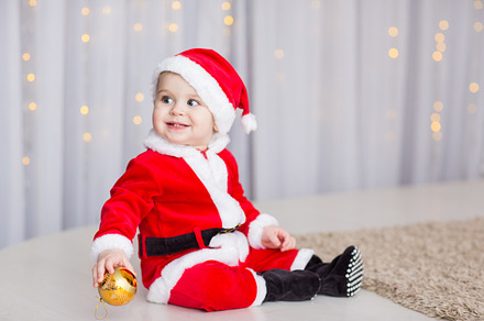 Funny baby boy weared in santa hat with golden christmas ball featuring