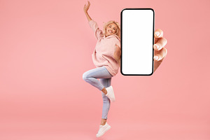 Positive woman jumping up and showing big blank cellphone screen advertising gr, a Photo by Prostock-Studio