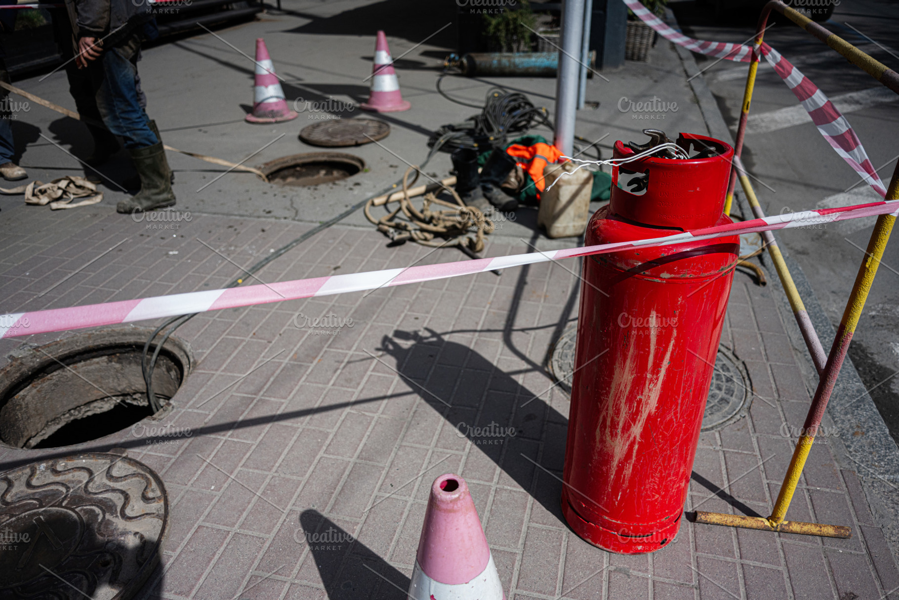Workers performing maintenance on manholes with safety barricades and equipment, a Photo by AS photostudio
