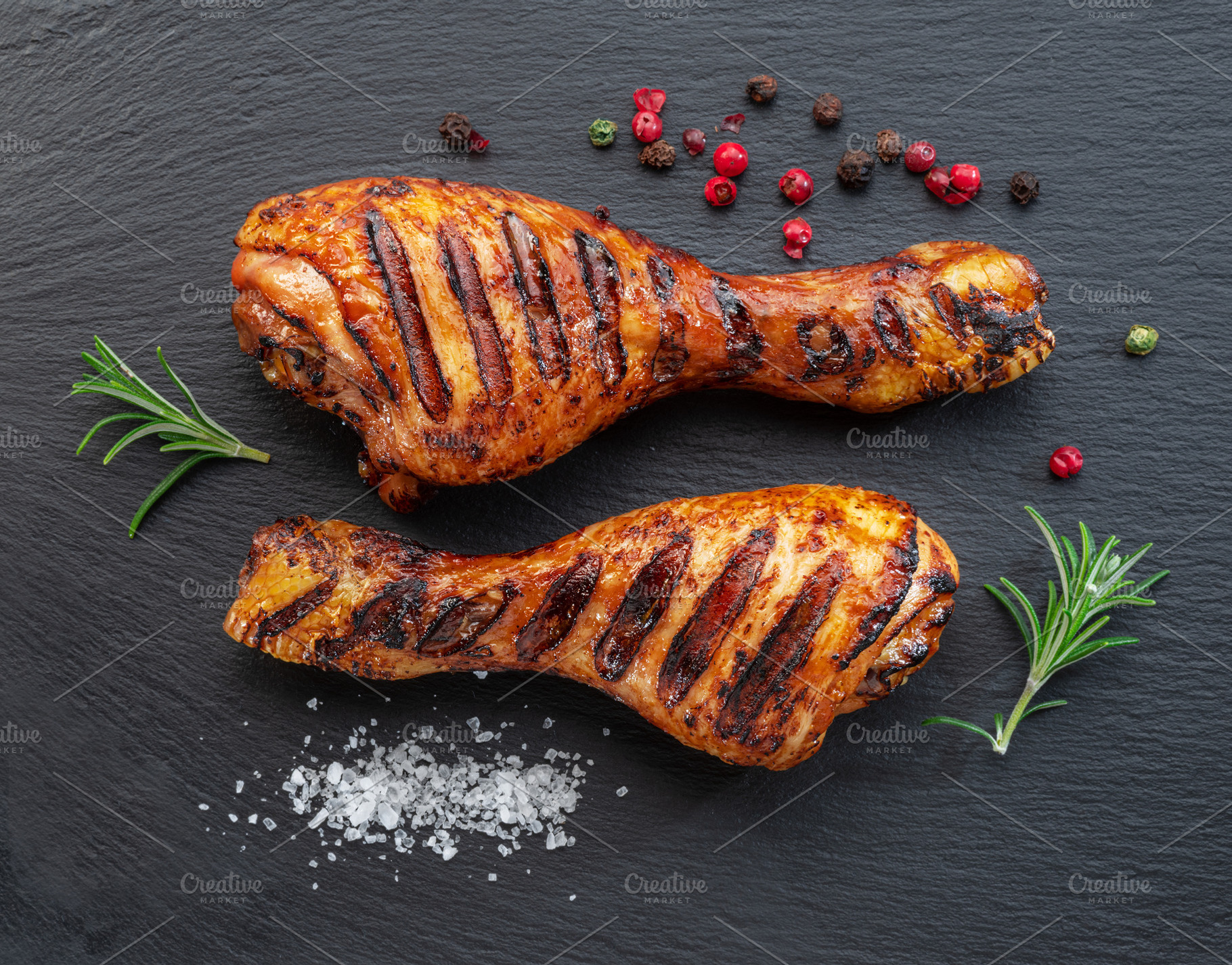Grilled delicious chicken legs or chicken drumsticks on black s, a Food & Drink Photo by Volff
