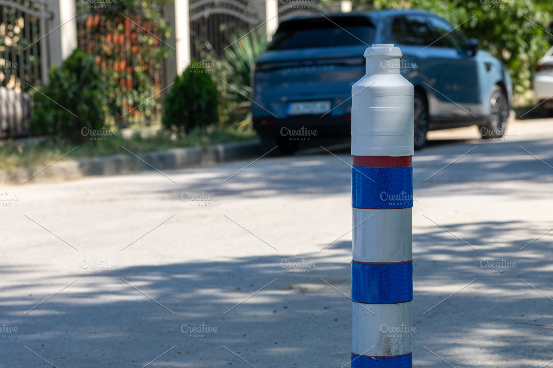 Plastic traffic bollard with blue reflective bands on a sunny city street, park, a Transportation Photo by Ales Munt