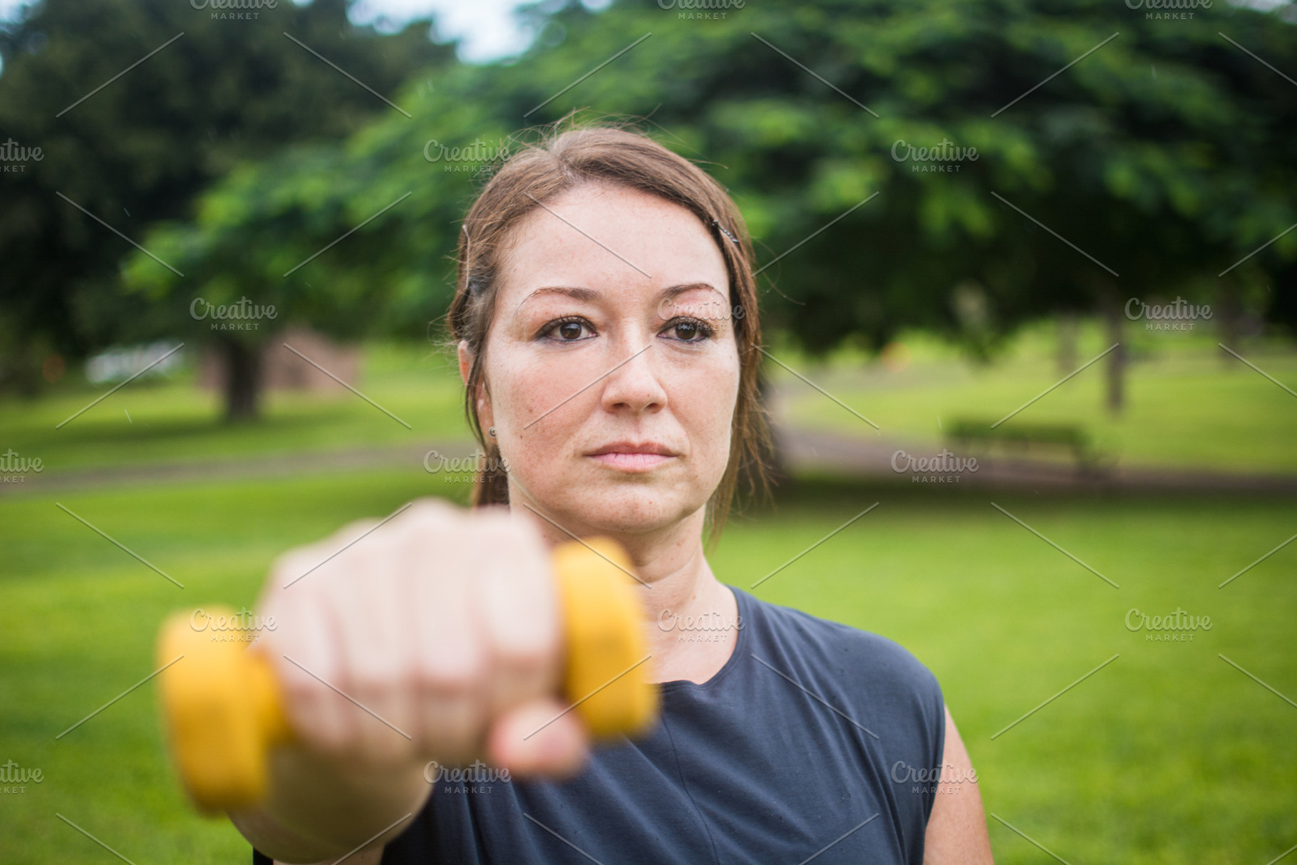Woman performing dumbbell front raise during outdoor strength workout, a Photo by etorres69