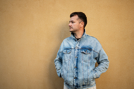 Side portrait of stylish man in jeans jacket against yellow wall, a Person Photo by AS photostudio