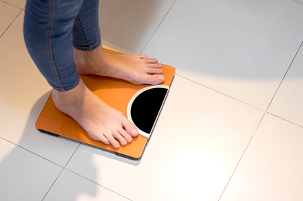Closeup of a Woman weighing herself on a bathroom scale