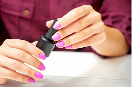 White woman holding nail polish, a Beauty & Fashion Photo by okskukuruza