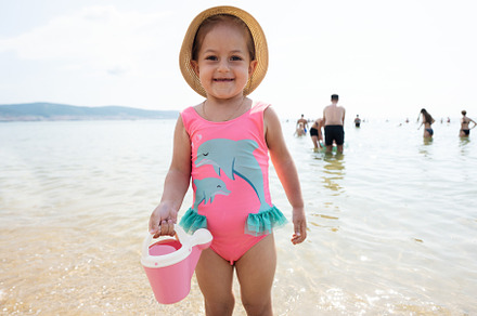 Cute little girl in pink swimsuit and hat holding bucket in the, a Person Photo by AS photostudio