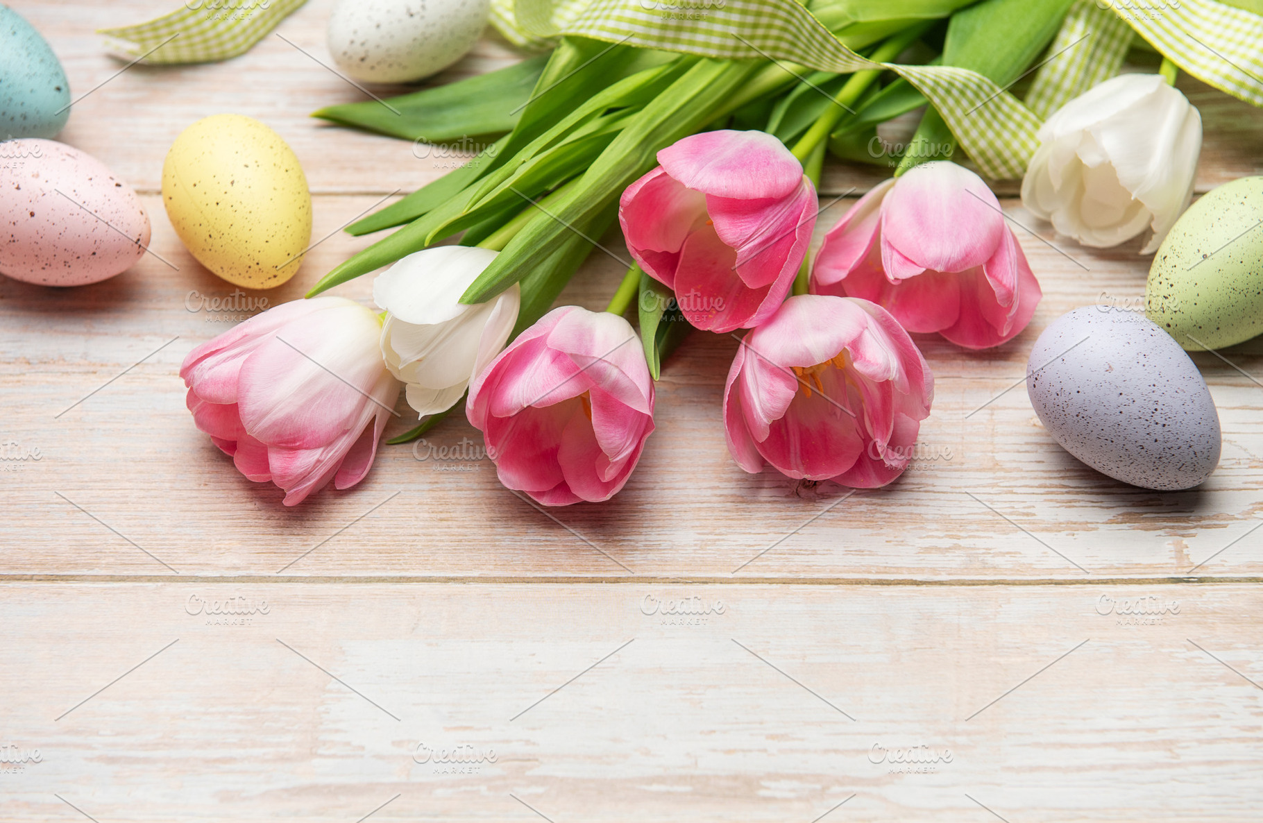 Easter eggs and pink tulips resting on white wooden table, a Holiday Photo by Olena Rudo