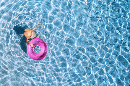 Aerial view of a young woman in hat swimming with pink swim ring, a Holiday Photo by den-belitsky