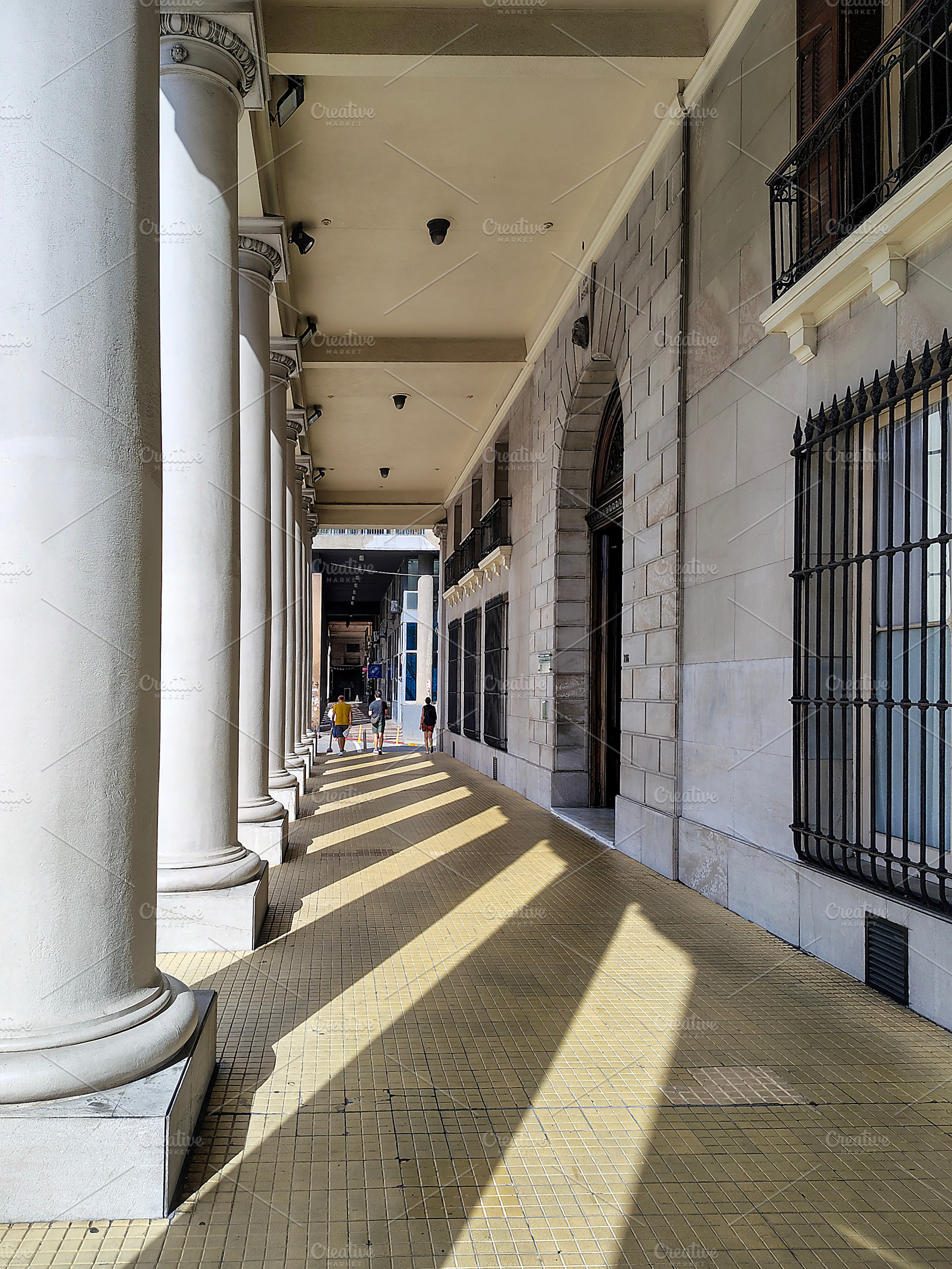 Sunlit columned corridor with shadows, an Architecture Photo by DanFLCreativo