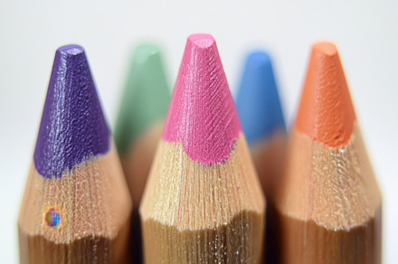 Brightly colored pencils stand in a, a Photo by Tanuart