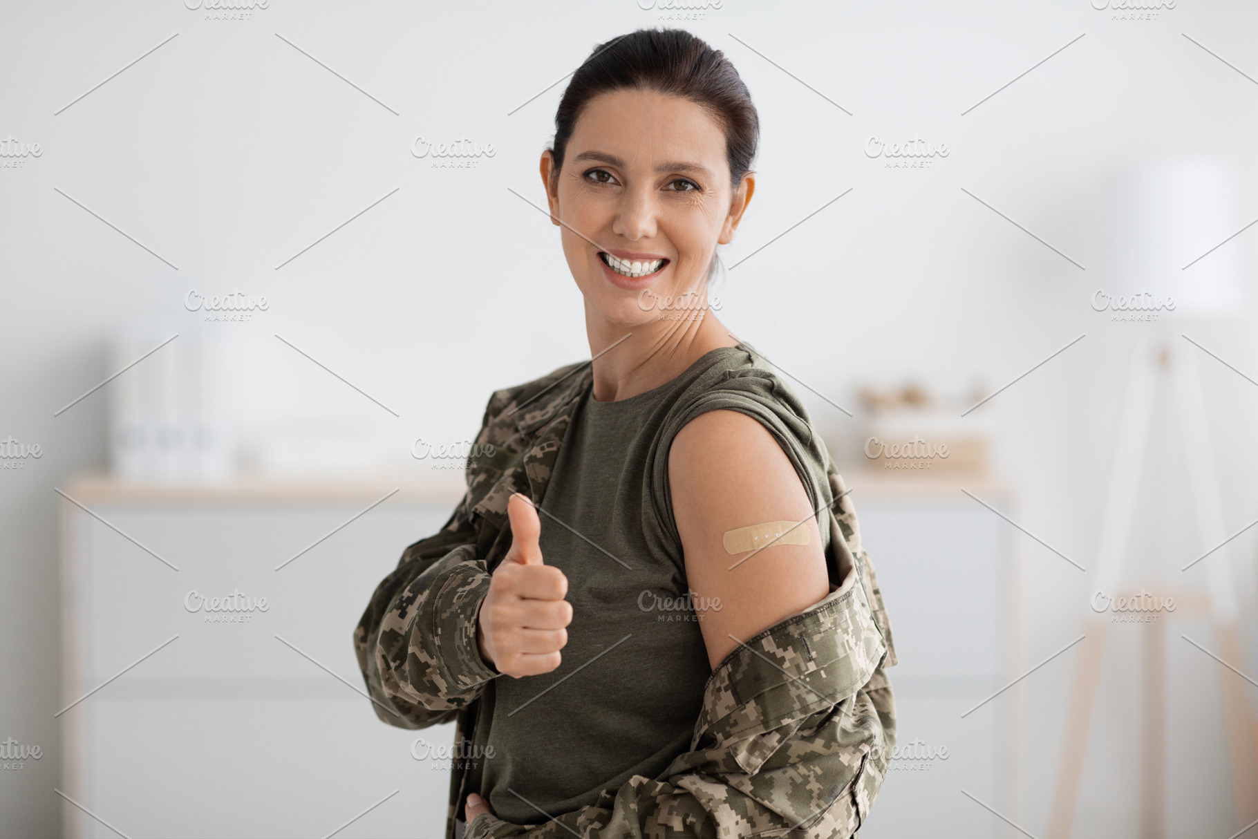 Covid-19 Vaccination. Smiling Military Woman In Uniform Demonstrating Arm With, a Photo by Prostock-Studio