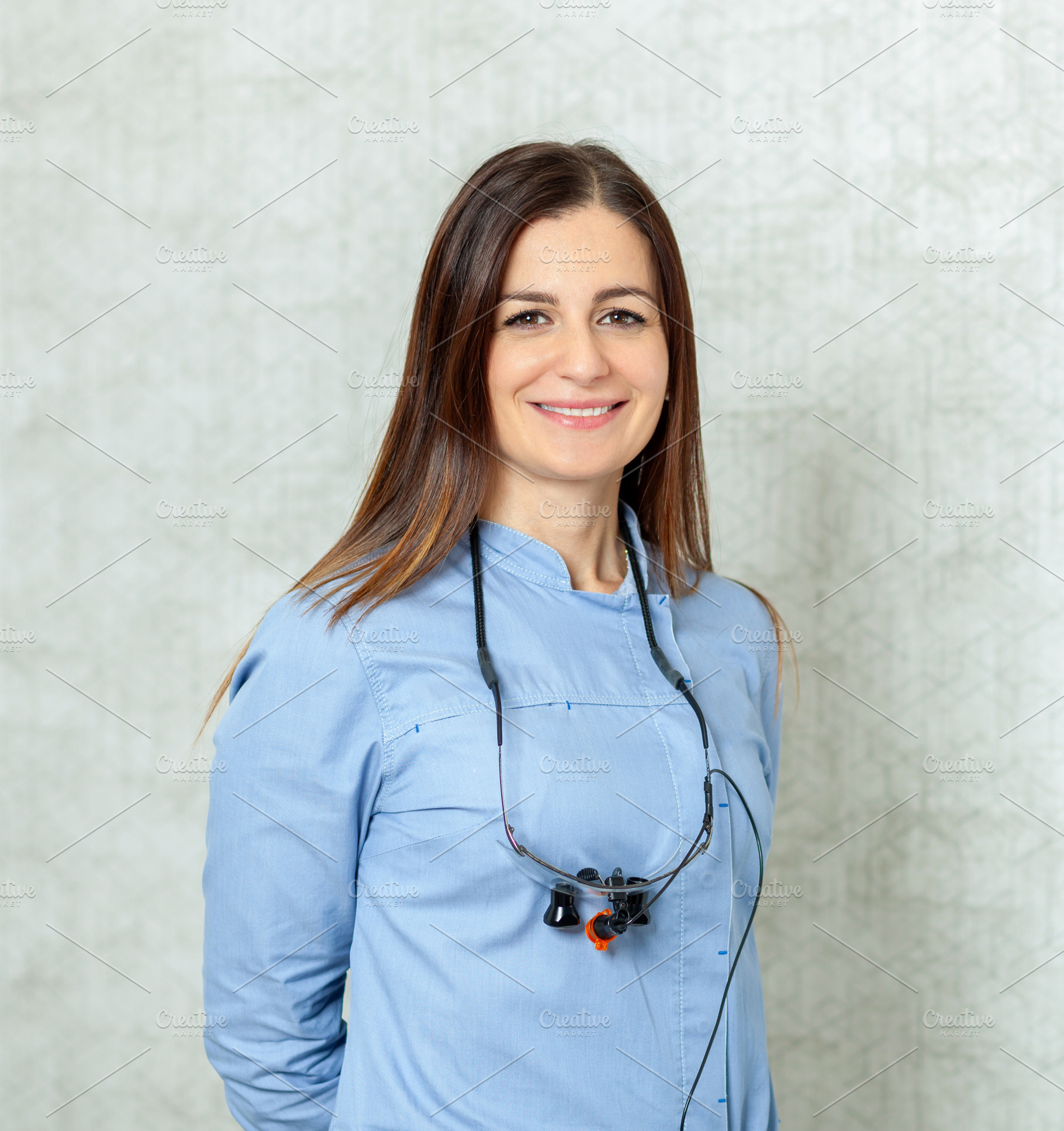 Portrait of smiling female dentist wearing magnifying glasses, a Health & Medical Photo by Antonio Gravante Market