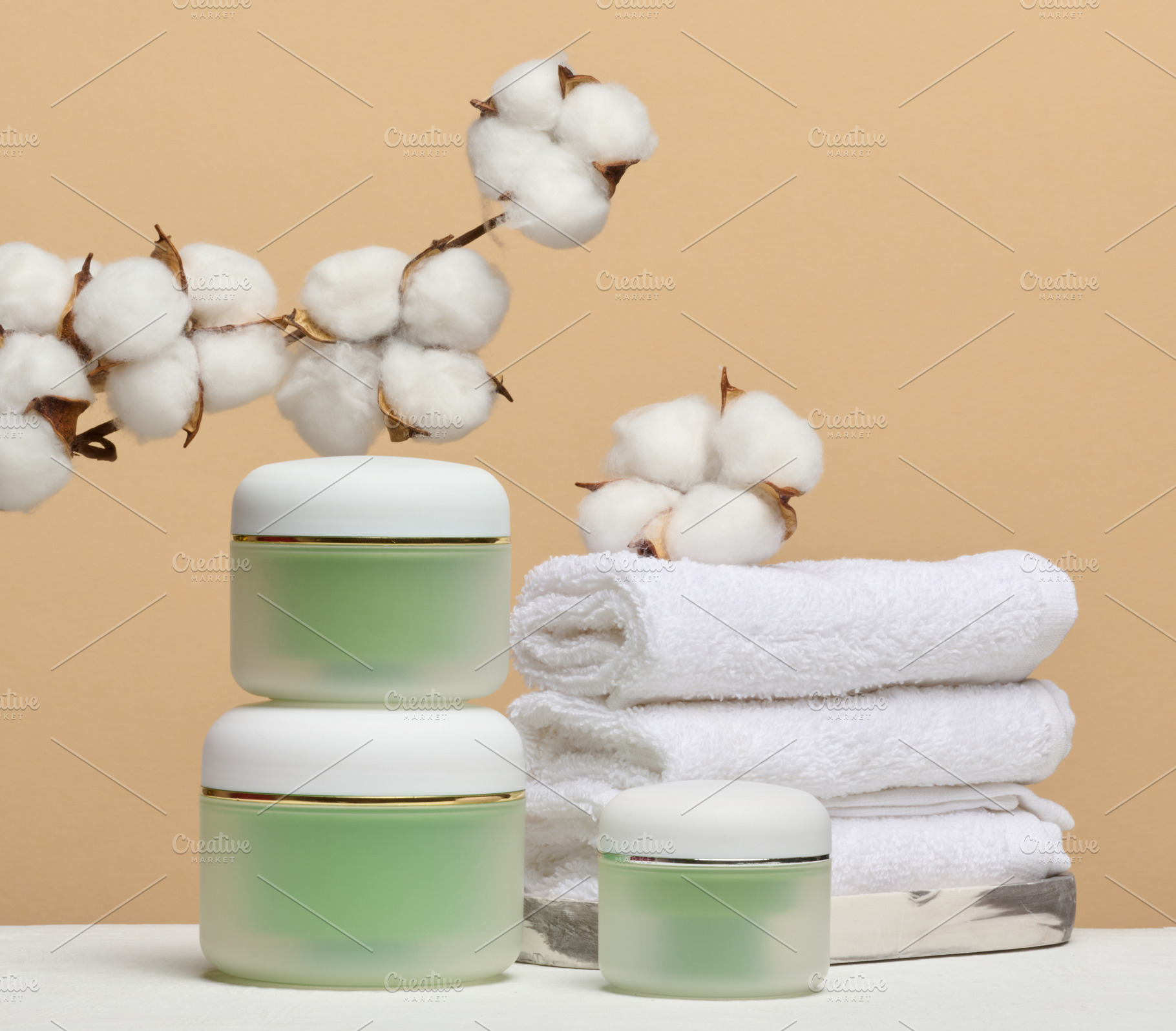 Green cosmetic jars, stack of white towels and branches of natur, a Beauty & Fashion Photo by ndanko