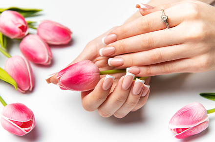 Woman holding pink tulip showing french manicure and diamond rin