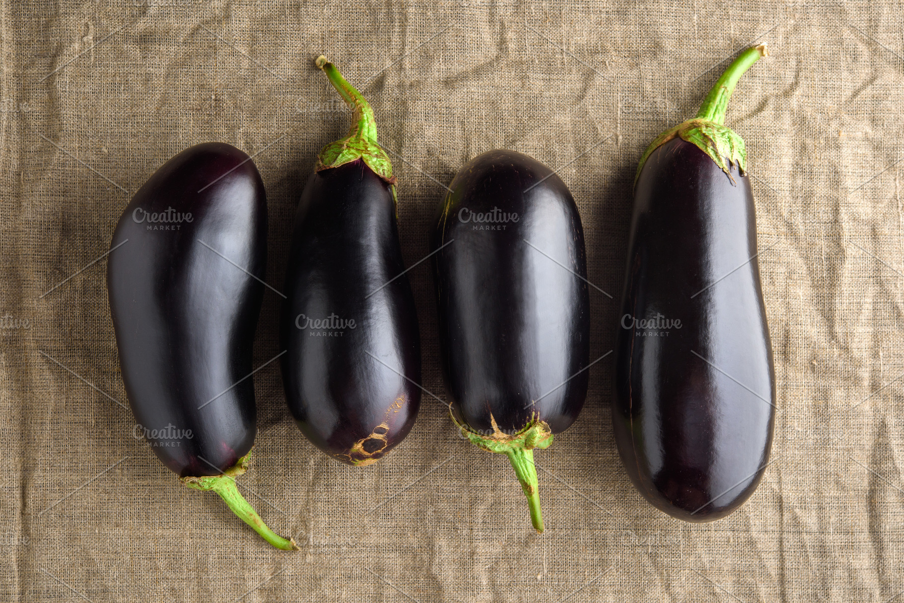 Four ripe black eggplants on linen c containing eggplant, aubergine, and fresh, a Food & Drink Photo by Edgieus