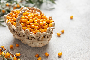 Fresh sea buckthorn berries overflowing a small basket on a text, a Food & Drink Photo by Olena Rudo