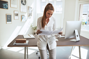 Young female architect standing in her office looking over desig