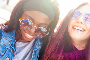 Two happy multi ethnic young women wearing sunglasses smiling together outdoors, a Person Photo by Antonio Gravante Market