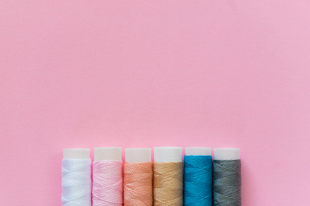 Thread spools with pink background containing thread, spool, and embroidery