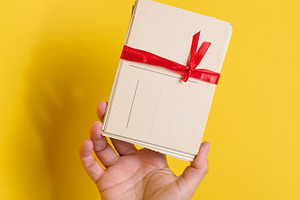 A person holding a stack of vintage postcards tied with a red ri, a Holiday Photo by ndanko