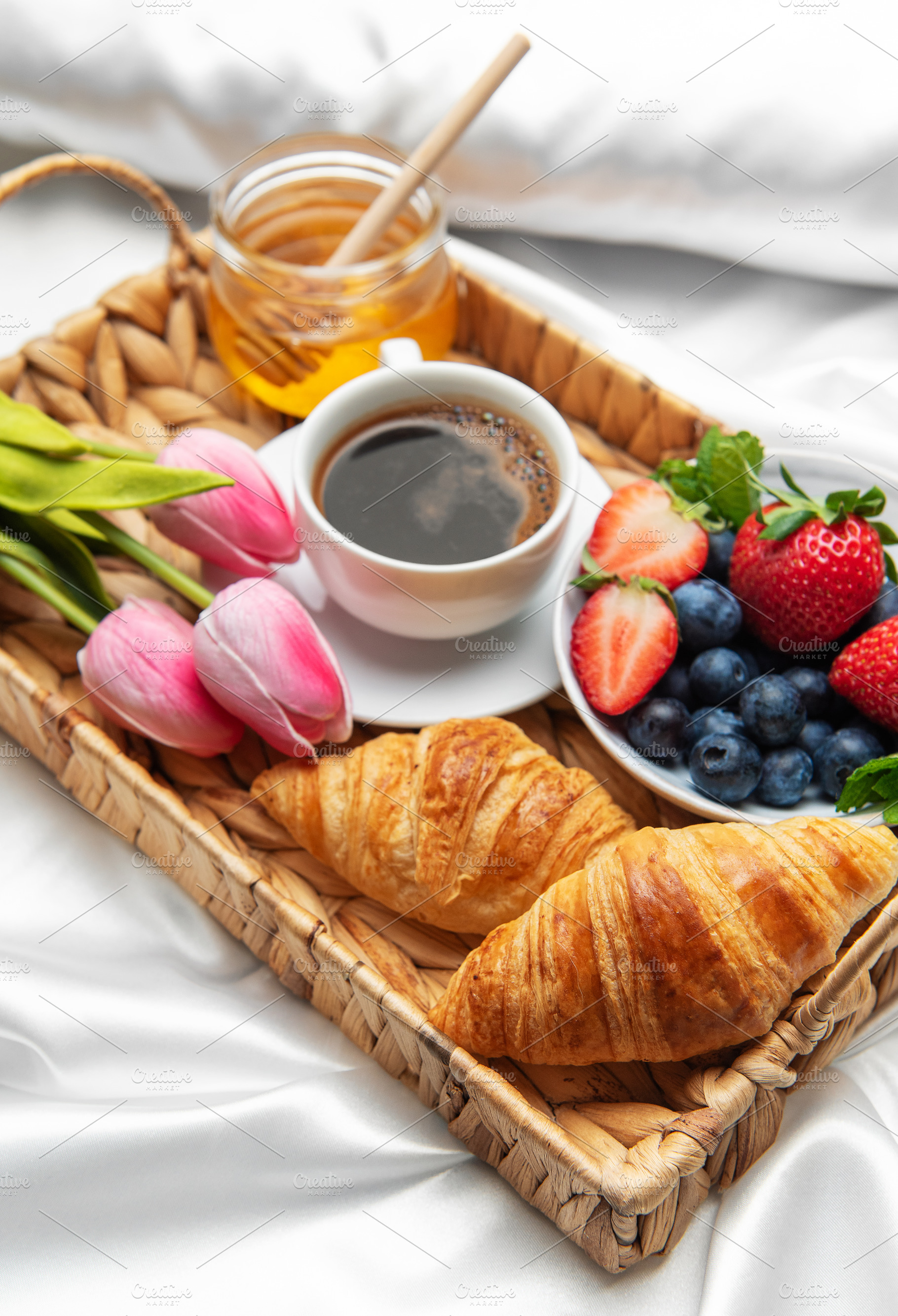 Romantic breakfast in bed with coffee, croissants, berries, hone, a Food & Drink Photo by Olena Rudo