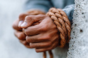 Hands tightly bound with rope against a rough wall in an intimate, intense mome, a Photo by AlyaAnd