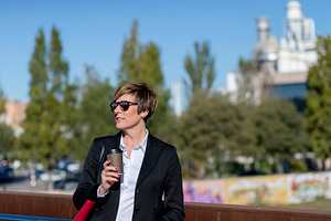 Businesswoman with coffee standing in city park, a Photo by RF Images