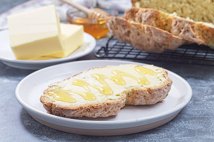 Freshly baked white Irish soda bread with butter and honey served on a plate, h