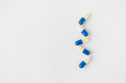 Medical pills-capsules, half blue on a white background, lying in a row. Flat l, a Health & Medical Photo by Artsaba Family