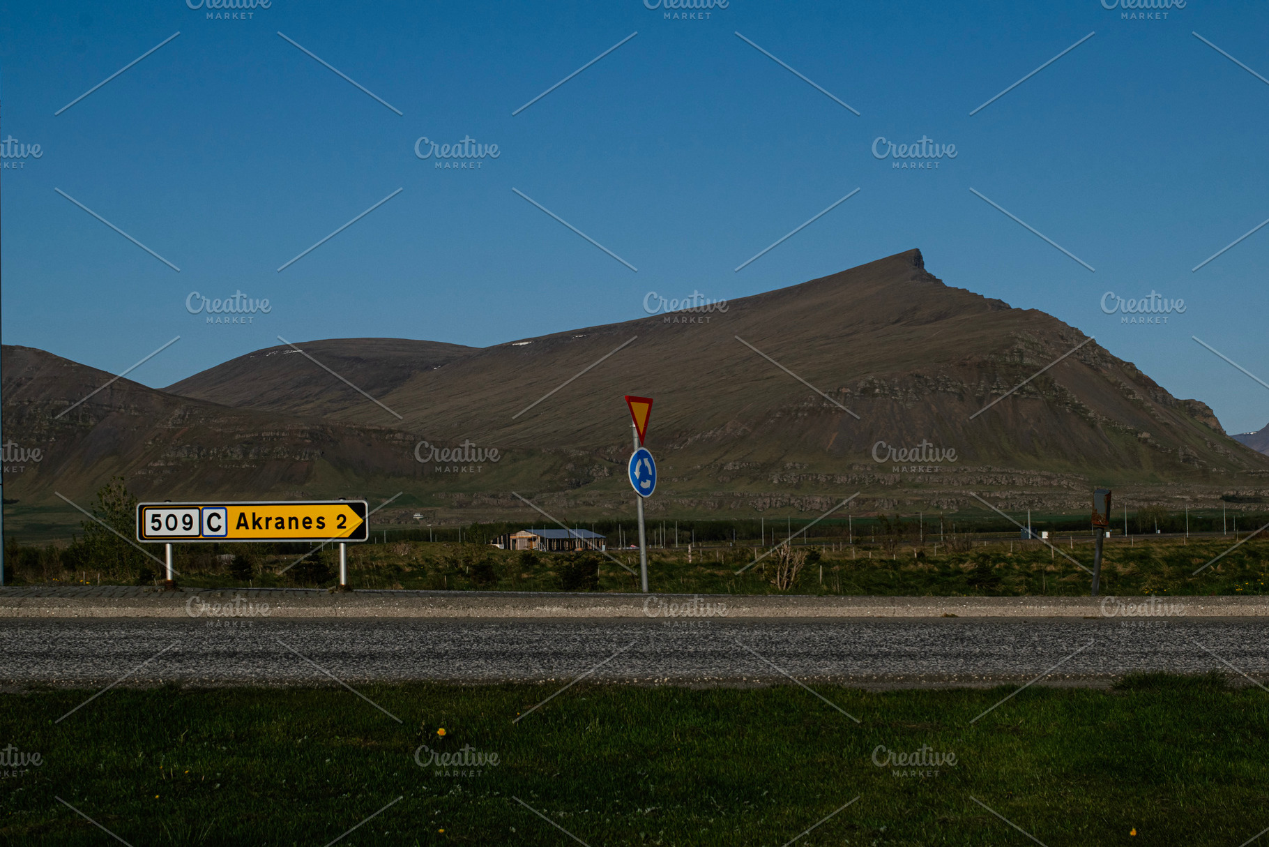 Countryside landscape near Akranes Iceland with road sign and prominent mountai, a Photo by AS photostudio