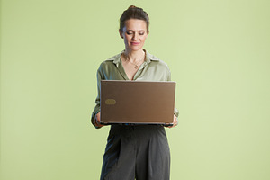 Woman in bright studio works on her laptop, focused, a Business Photo by Alliance Images