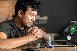 Focused man playing online poker on laptop, a Sports & Recreation Photo by Davizro's Market